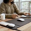 Person using a laptop with a mouse on a desk, wearing a beige sweater.
