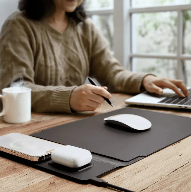 Person using a laptop with a mouse on a desk, wearing a beige sweater.