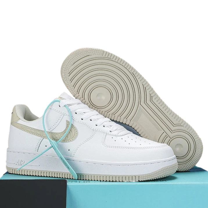 A pair of Nike Air Force 1 Low sneakers in white with beige heel accents and a mint green shoelace, displayed on a light blue box. One shoe is shown in profile, and the other is positioned behind it to display the sole.